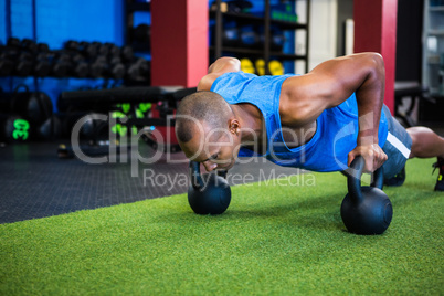 Man doing push-ups with kettlebells