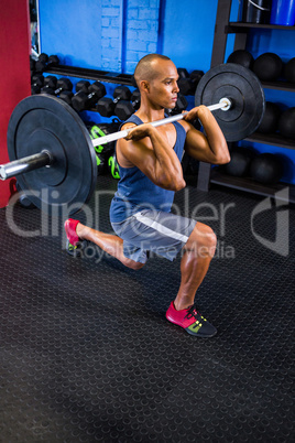 Determined man lifting barbell in fitness studio