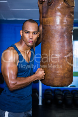 Determined young man standing by punching bag