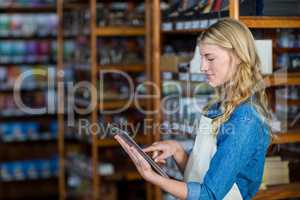 Female staff using digital tablet in supermarket