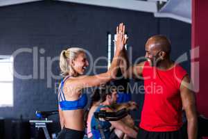 Smiling friends giving high-five in gym