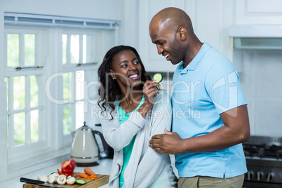 Woman feeding man a slice of cucumber