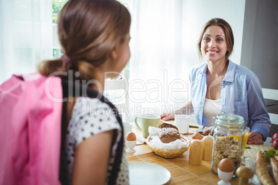 Mother interacting with her daughter while having breakfast