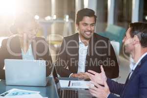 Businesswoman discussing with colleagues over laptop