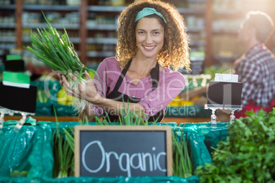 Smiling staff holding vegetable in organic section