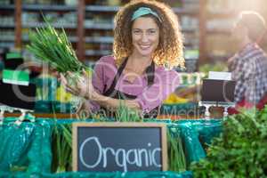 Smiling staff holding vegetable in organic section