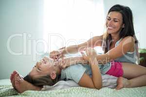 Mother and daughter playing on bed