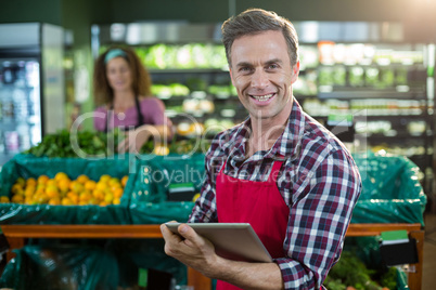 Smiling staff using digital tablet in organic section