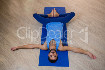 Man doing reclining bound angle pose on exercise mat