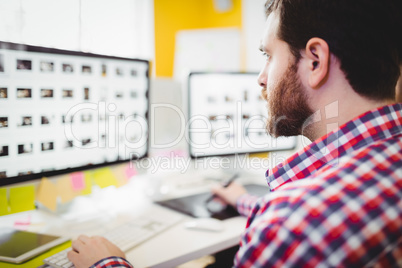 Close-up of editor concentrating on photographs in computer at creative office