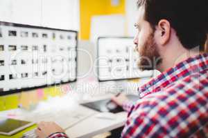 Close-up of editor concentrating on photographs in computer at creative office