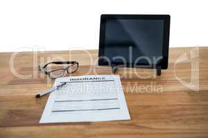 Digital tablet, insurance form, spectacle and pen on desk