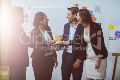 Group of businesspeople shaking hands with each other in front of whiteboard