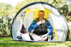 Portrait of smiling hiker having a cup of coffee in tent