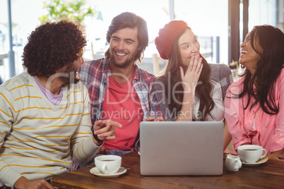 Laughing friends enjoying coffee with laptop