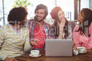 Laughing friends enjoying coffee with laptop