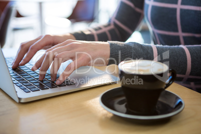 Woman using laptop with coffee on table