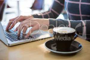 Woman using laptop with coffee on table