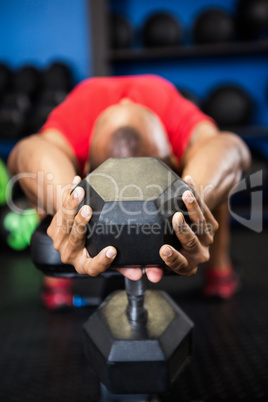 Athlete exercising with dumbbell on bench