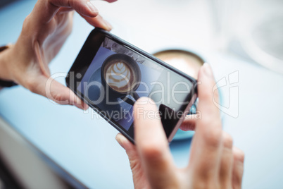 Woman taking photo of a coffee from mobile phone