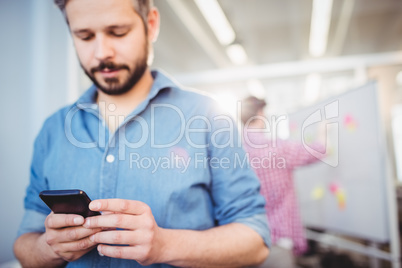 Businessman texting on cellphone at creative office