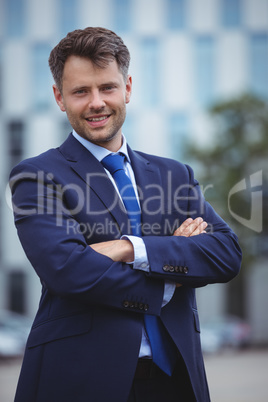 Portrait of handsome businessman standing with arms crossed