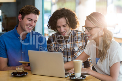 Friends using digital tablet and laptop in cafÃ?Â©