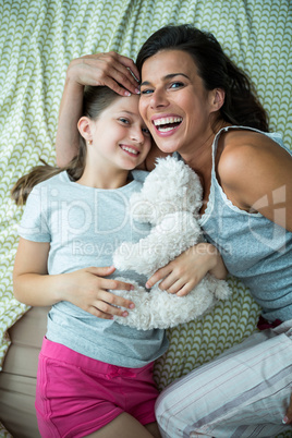 Mother and daughter playing on bed at home