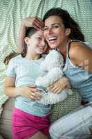 Mother and daughter playing on bed at home