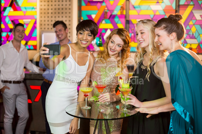 Group of friends taking selfie from mobile phone while having cocktail