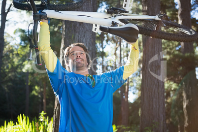 Male mountain biker carrying bicycle in the forest