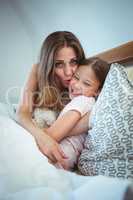 Mother kissing daughter on bed