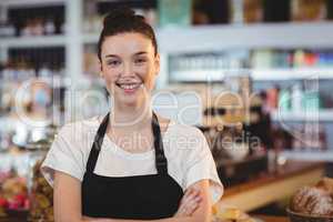 Portrait of smiling waitress standing with arms crossed
