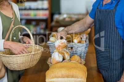 Mid section of woman purchasing bread at bakery store