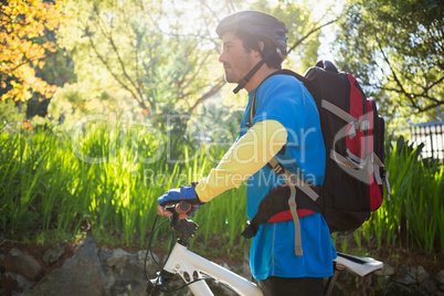 Male mountain biker with bicycle in the forest