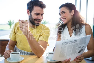 Couple reading newspaper while having coffee