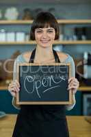 Smiling waitress showing slate with open sign