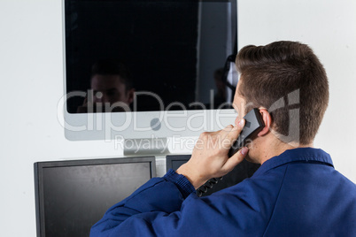 Security officer talking on telephone while looking at computer monitors