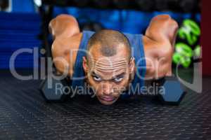 Portrait of serious man doing push-ups with dumbbell