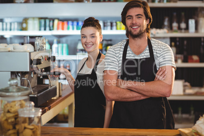 Portrait of waiter and waitress making cup of coffee at counter