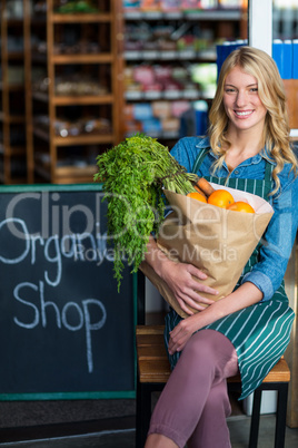Smiling woman with grocery bag sitting in organic shop