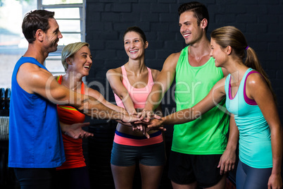 Happy athletes putting hands together in gym