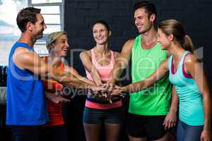 Happy athletes putting hands together in gym
