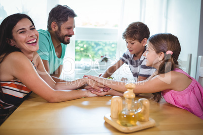 Parents and kids putting their hands together on table