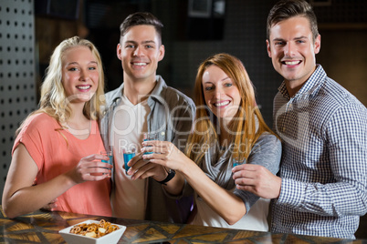 Group of friends standing at bar counter and having tequila shots
