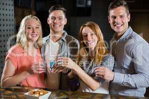 Group of friends standing at bar counter and having tequila shots