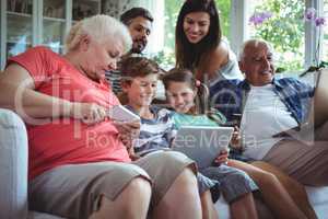 Happy multi-generation family using laptop, mobile phone and digital tablet