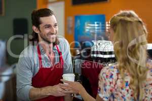 Male staff giving coffee to woman in coffee shop