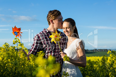 Man kissing on woman forehead in mustard field