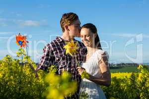 Man kissing on woman forehead in mustard field